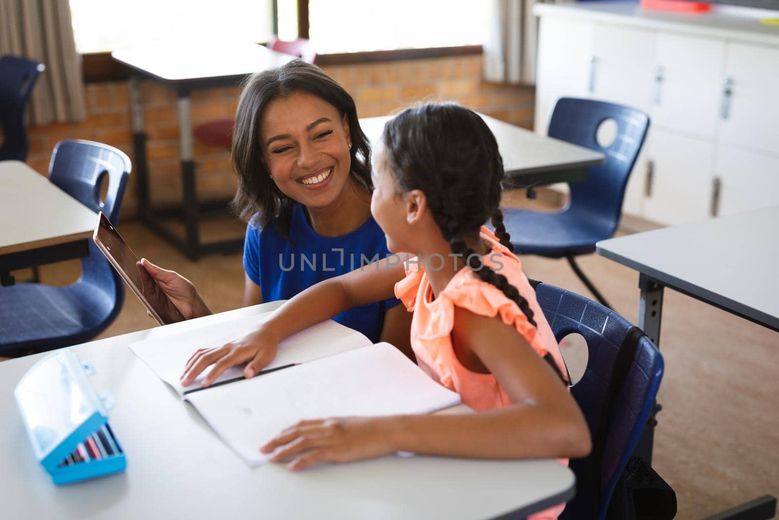 African american female teacher with digital tablet teaching a girl at elementary school by Wavebreakmedia