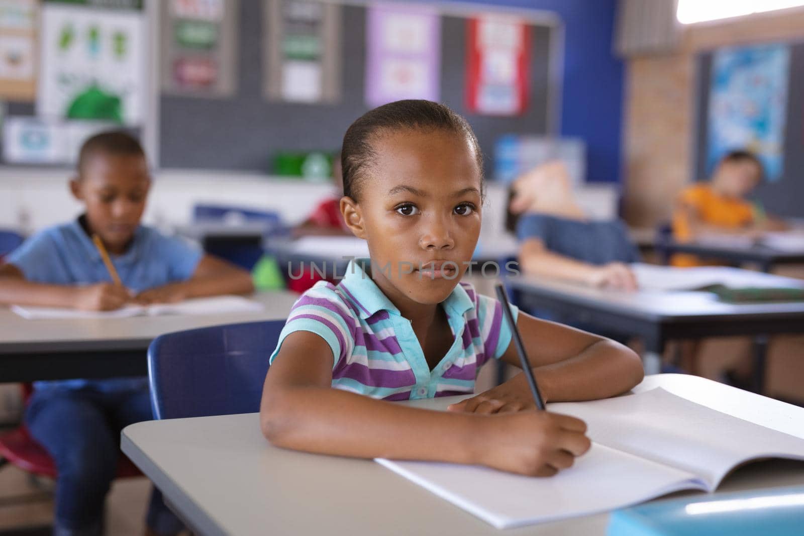 Portrait of african american girl sitting on her desk in the class at school by Wavebreakmedia