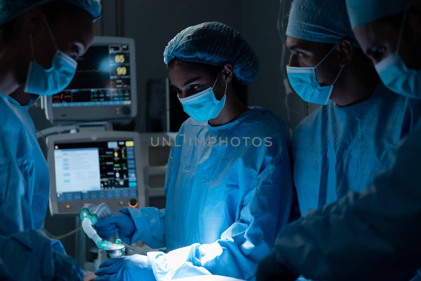 Diverse surgeons with face masks and protective clothing during operation in hospital. operating theatre. medicine, health and healthcare services during covid 19 coronavirus pandemic.