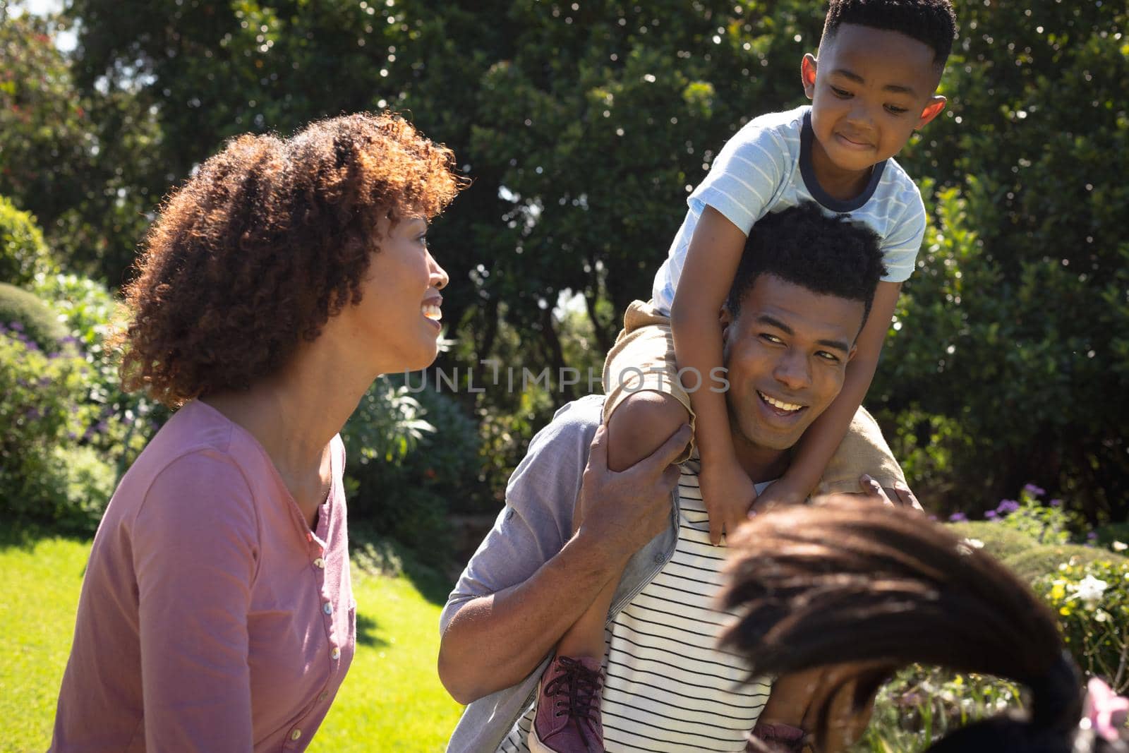 Happy african american couple with son outdoors, playing in sunny garden. family enjoying quality free time together.