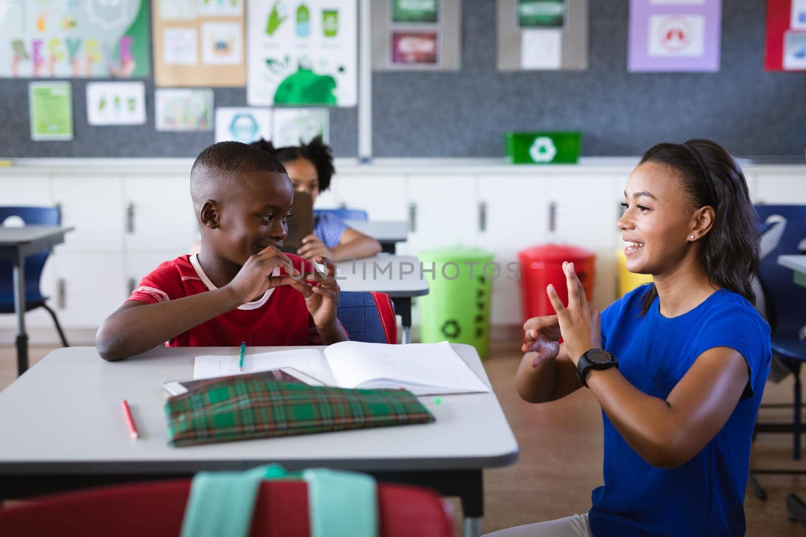 African american female teacher and boy talking in hand sign language at elementary school by Wavebreakmedia