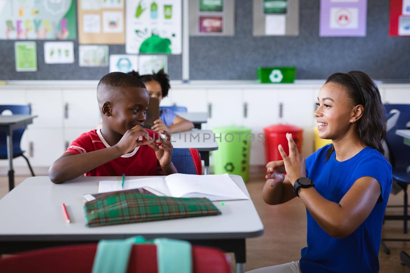 African american female teacher and boy talking in hand sign language at elementary school. school and education concept