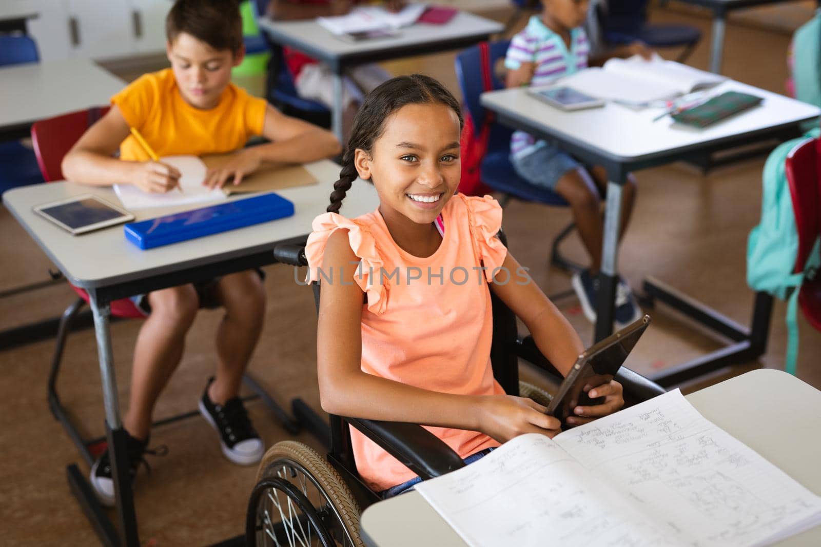 Portrait of disabled african american girl smiling while sitting on wheelchair at elementary school. school and education concept
