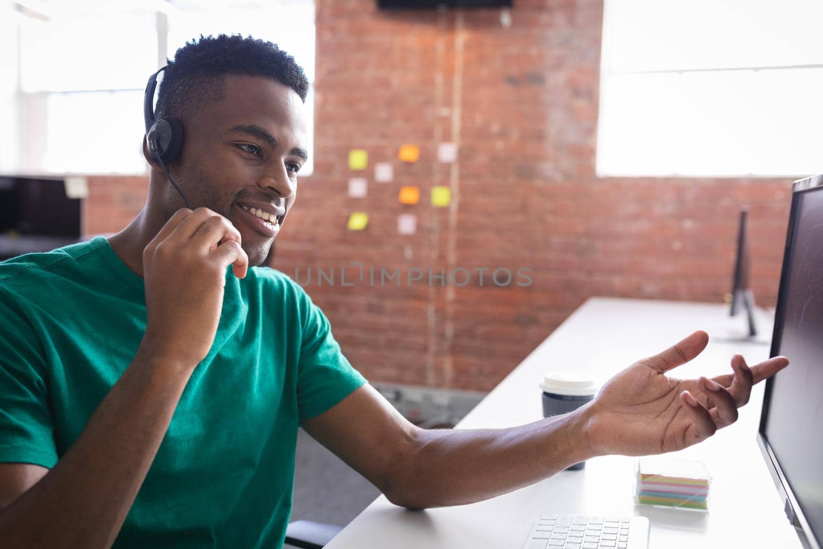 African american businessman having video call sitting in front of computer using headphones by Wavebreakmedia