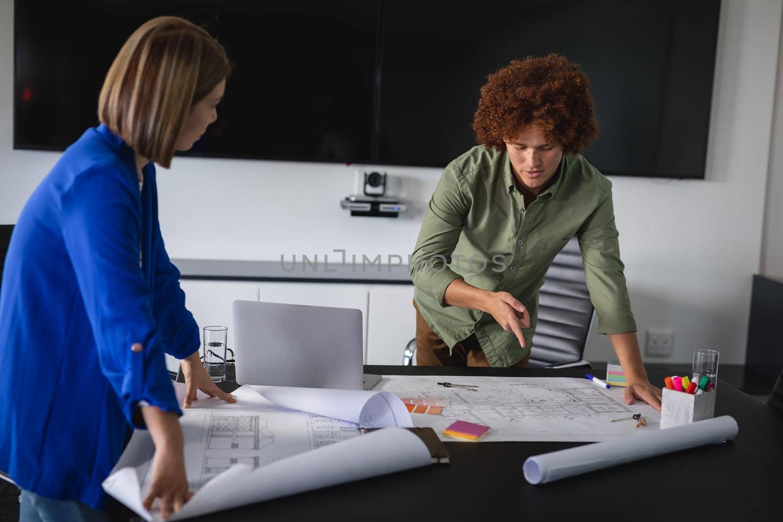 Diverse male and female colleagues in office discussing over blueprint document. independent creative design business.