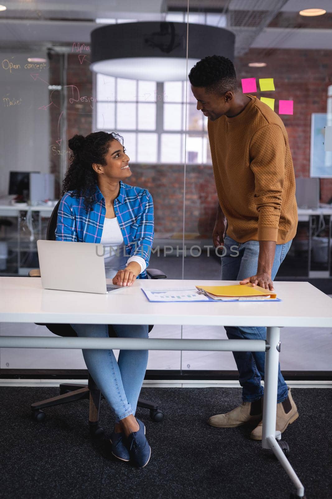 Diverse male and female colleagues at work discussing and looking at laptop. independent creative design business.