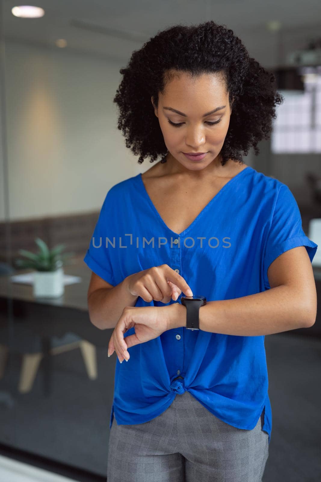 African american businesswoman checking smartwatch standing in office. working in business at a modern office.