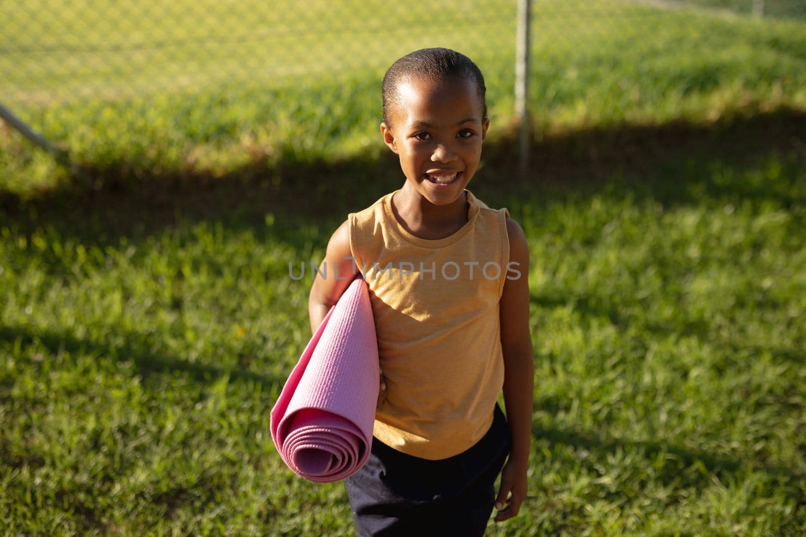Portrait of african american girl smiling while while standing in the garden at school by Wavebreakmedia