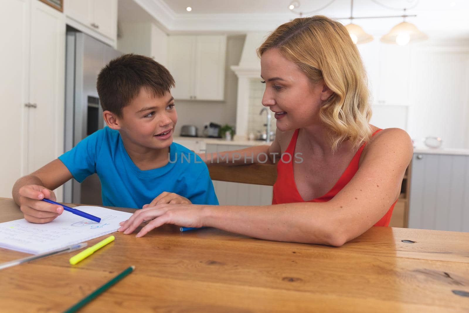 Caucasian mother doing homework with her son and smiling at home by Wavebreakmedia