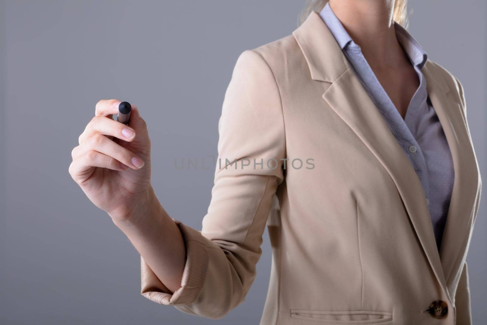 Midsection of caucasian businesswoman holding pen, isolated on grey background by Wavebreakmedia