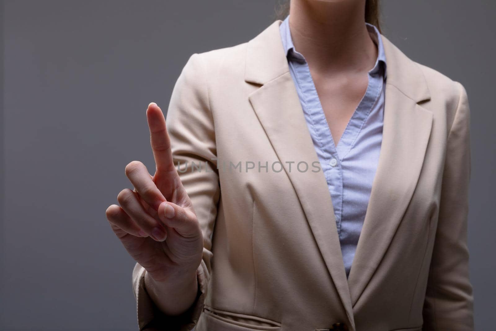 Midsection of caucasian businesswoman touching virtual interface on grey background. business technology, communication and growth concept.