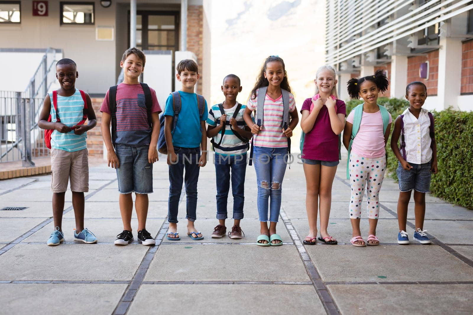 Portrait of group of diverse students smiling together while standing at school. school and education concept