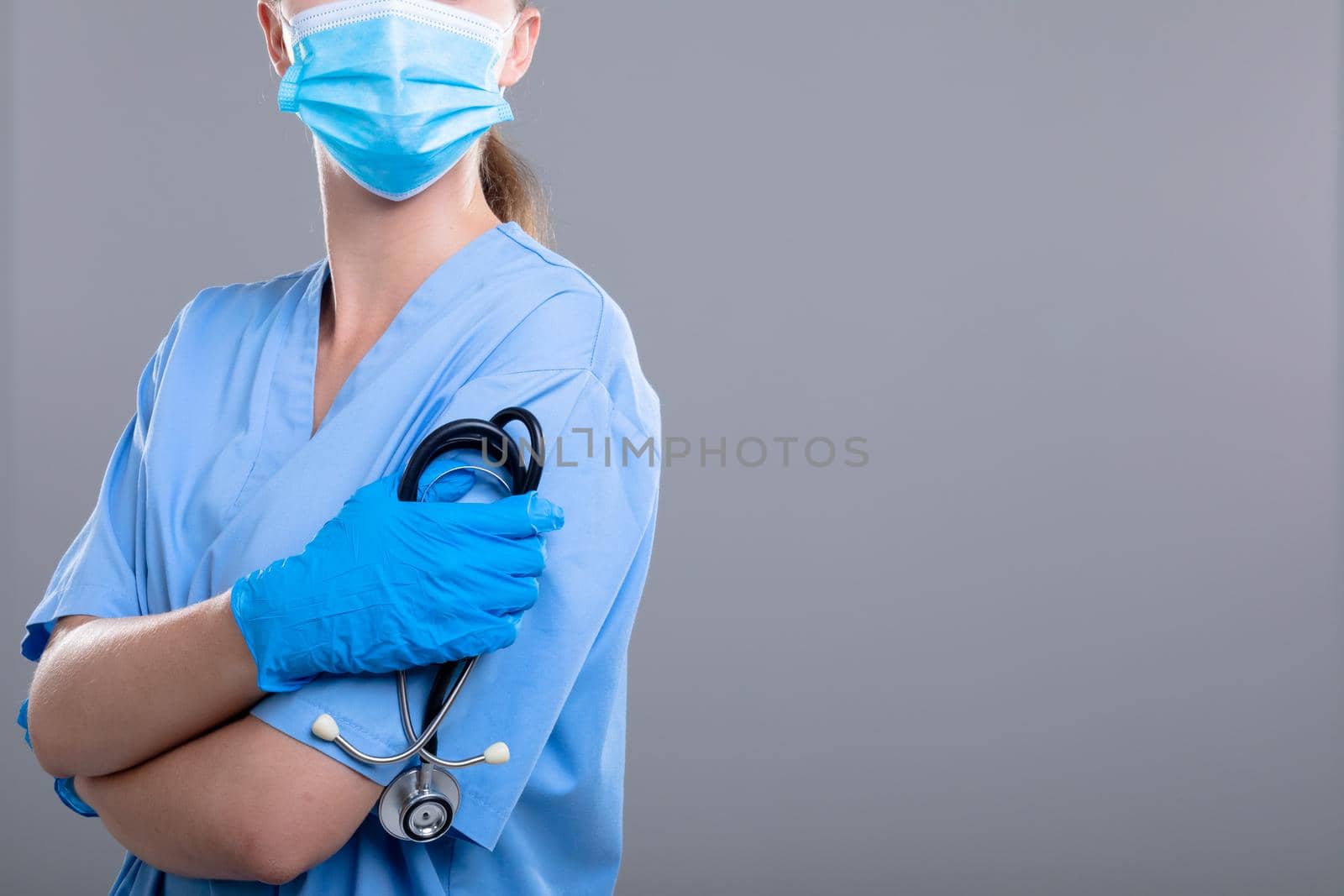 Caucasian female doctor wearing face mask holding stethoscope. medical and healthcare technology concept during covid 19 coronavirus pandemic concept.