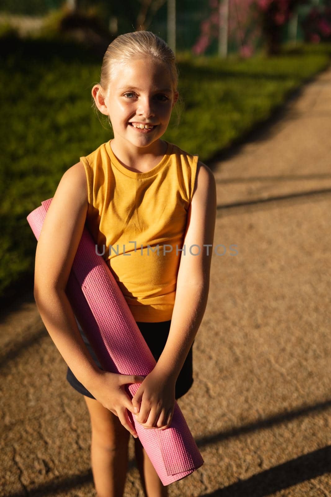 Portrait of caucasian girl smiling while while standing in the garden at school. school and education concept