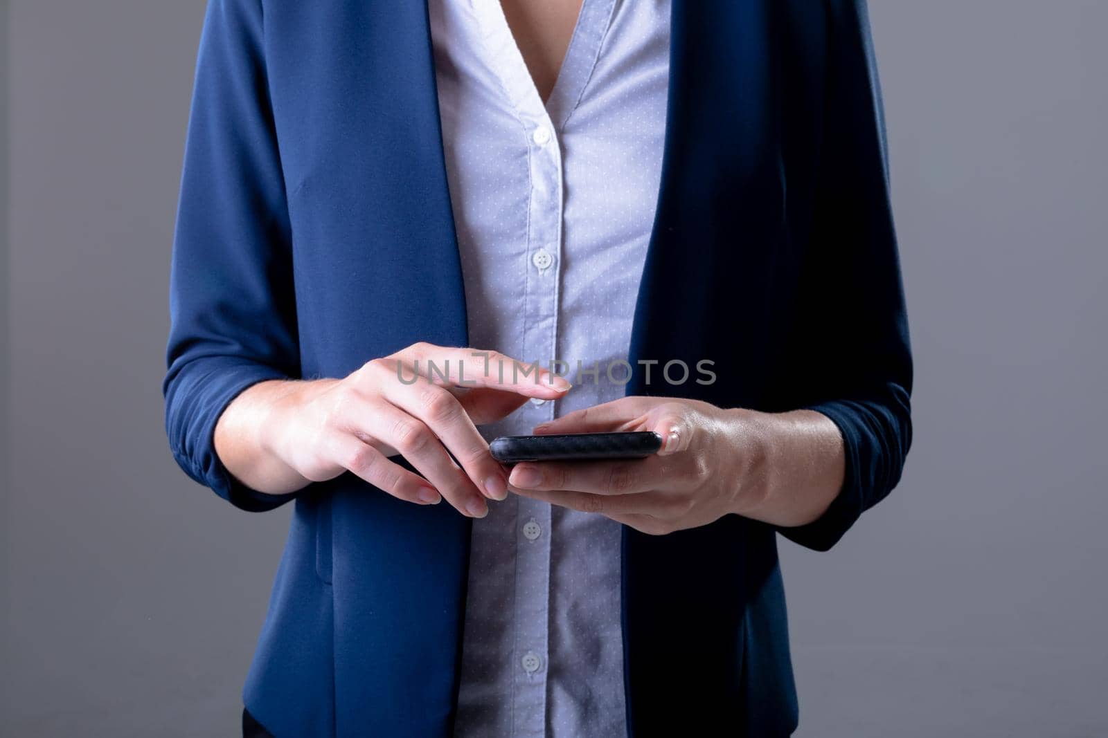 Midsection of caucasian businesswoman using smartphone, isolated on grey background by Wavebreakmedia