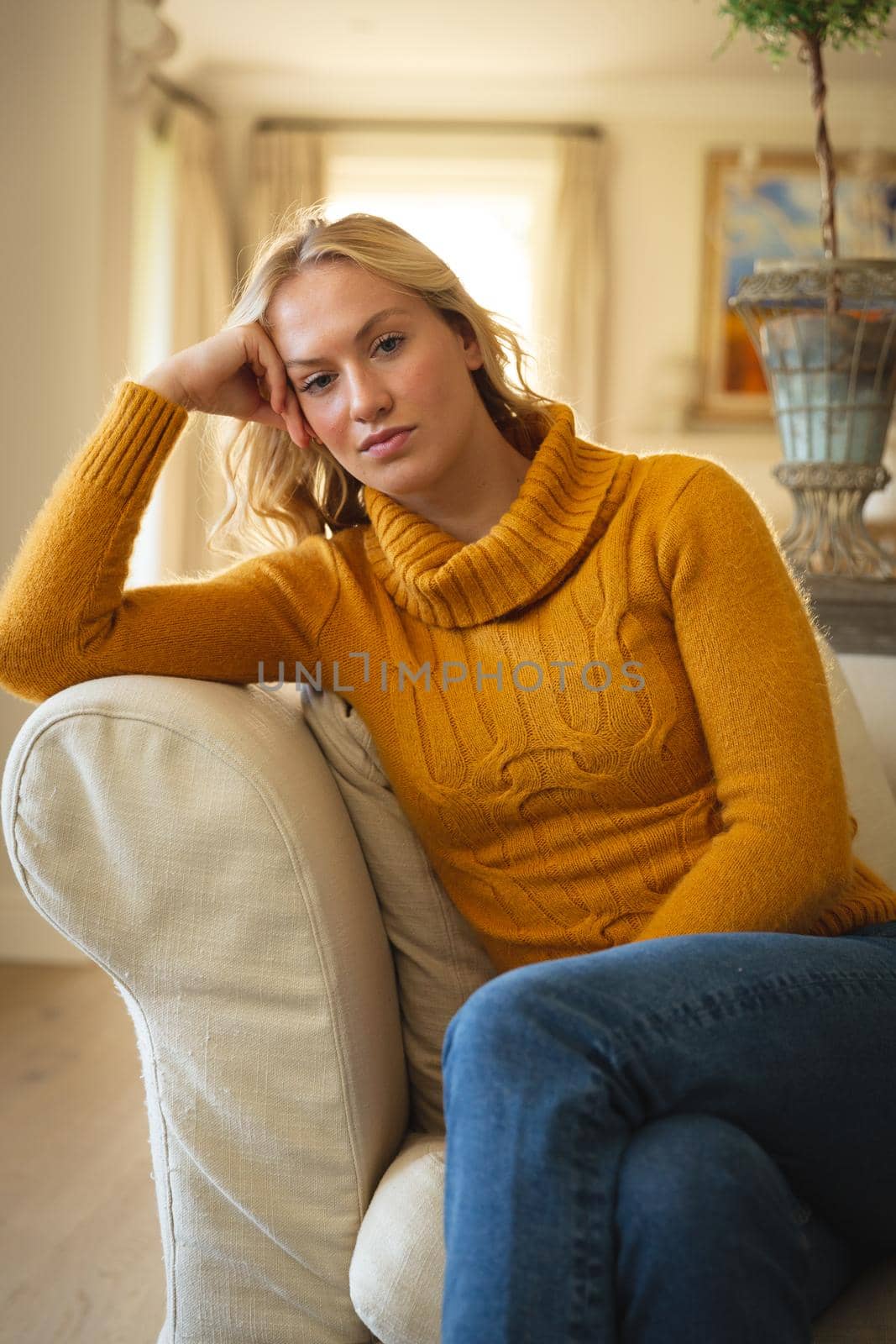 Portrait of thoughtful caucasian woman sitting on couch in luxury living room, leaning and listening. spending free time at home.