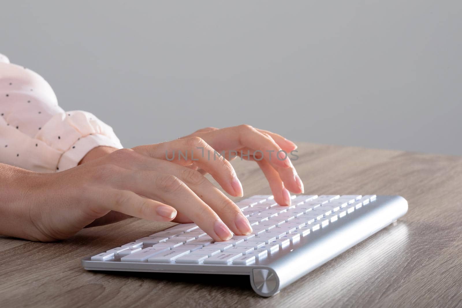 Midsection of caucasian businesswoman typing on keyboard, isolated on grey background by Wavebreakmedia