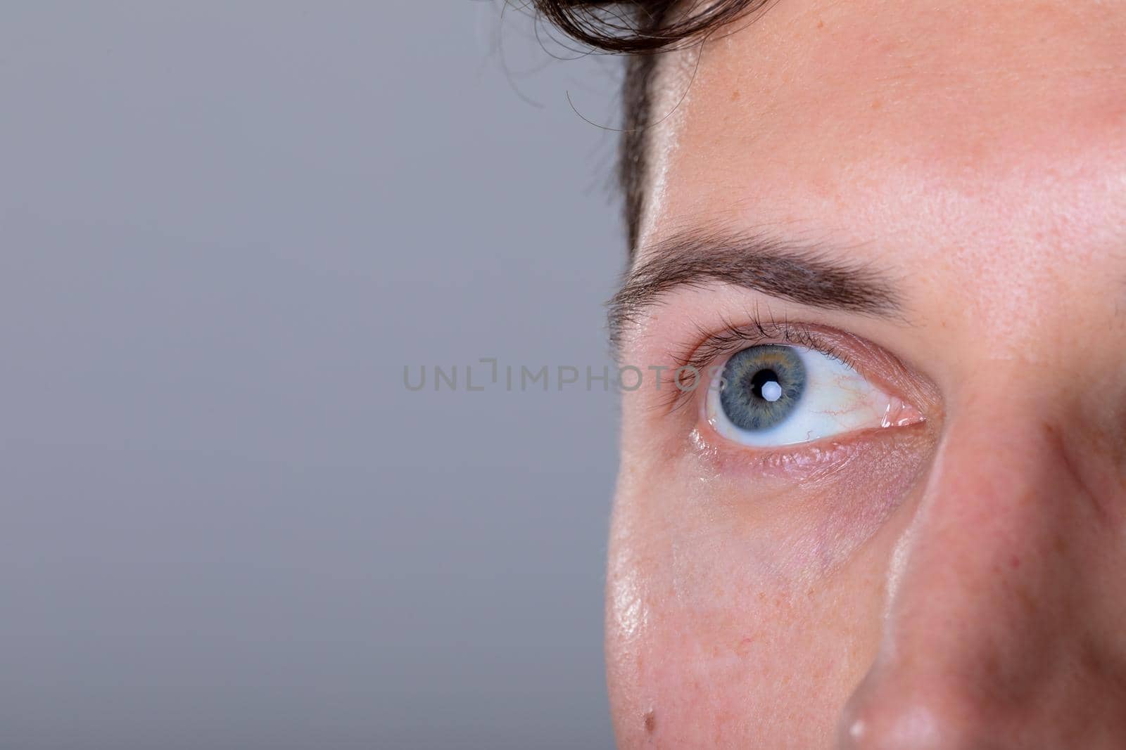 Close up of blue eye of caucasian businessman, isolated on grey background by Wavebreakmedia