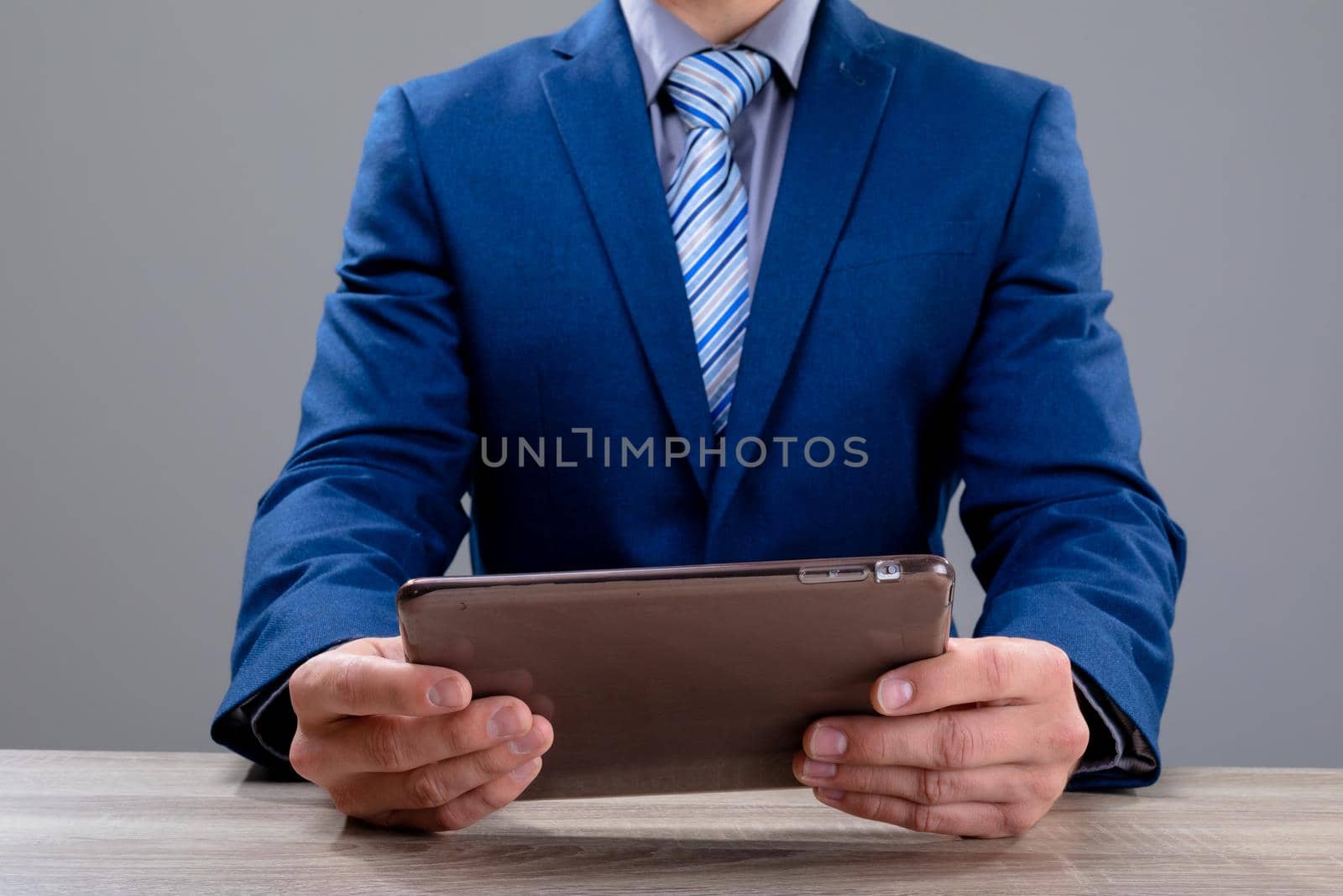 Midsection of caucasian businessman using tablet, isolated on grey background by Wavebreakmedia