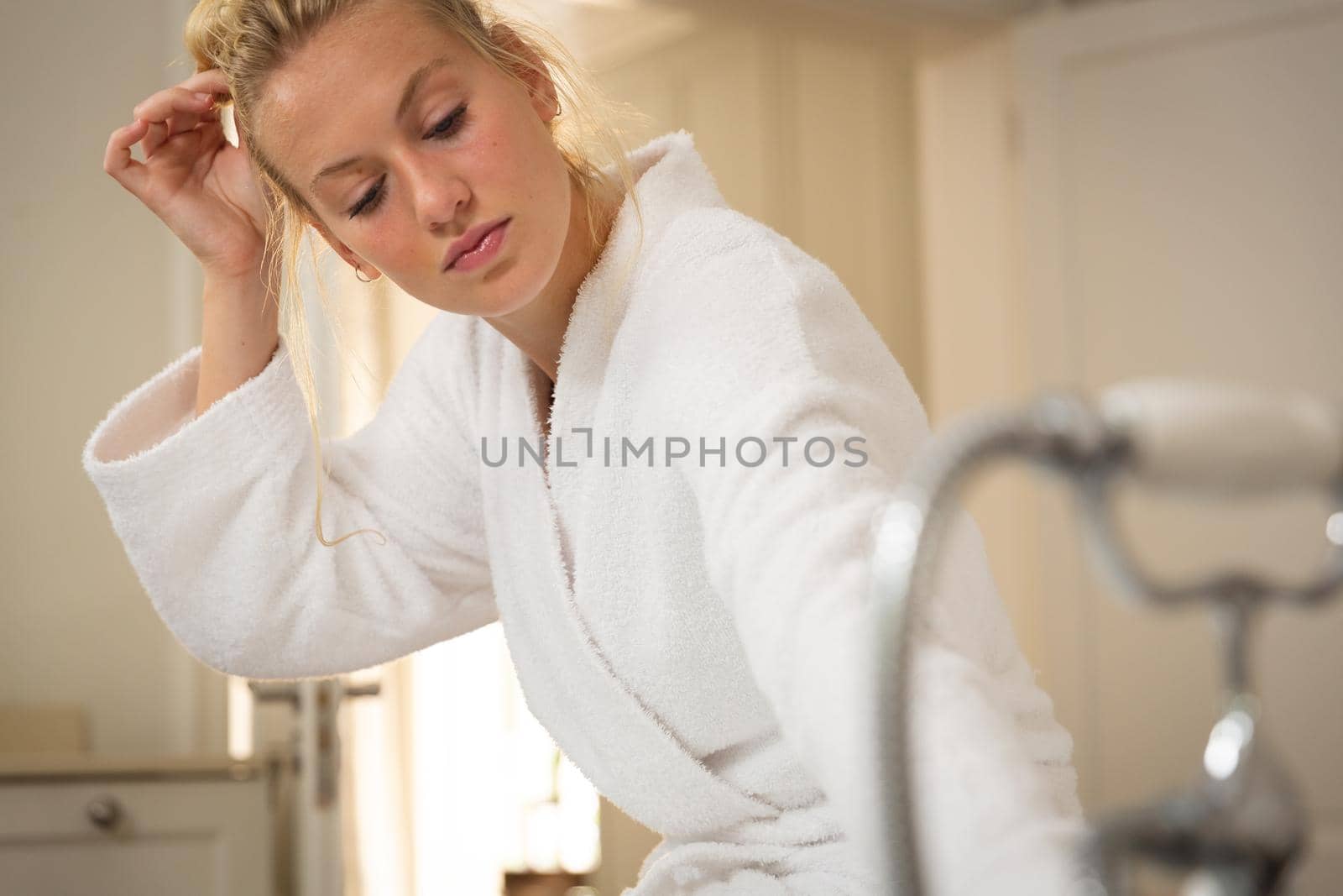 Caucasian woman in bathroom wearing bathrobe, running a bath. health, beauty and wellbeing, spending quality time at home.