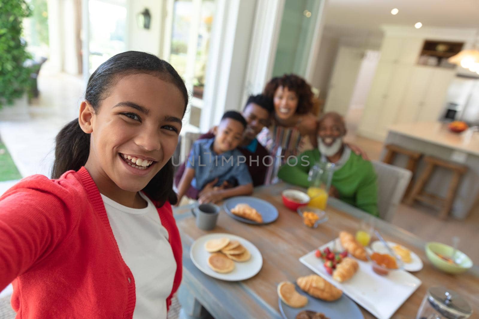 Happy african american family sitting at breakfast table taking selfie and smiling by Wavebreakmedia