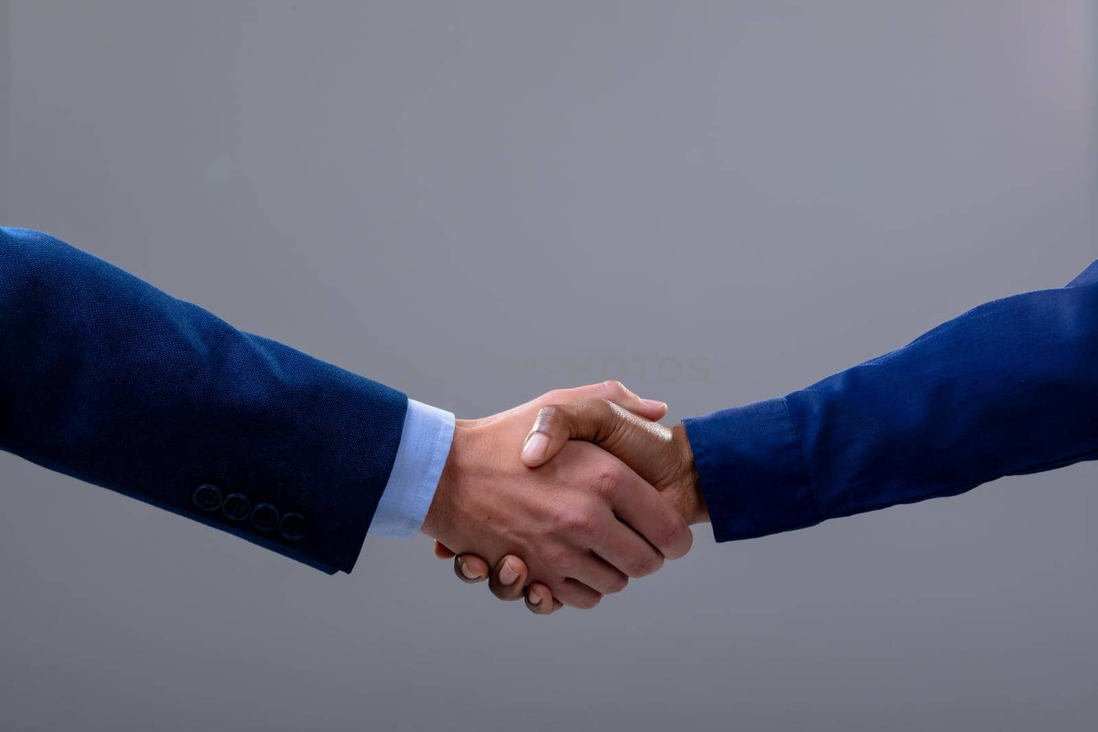 Caucasian and african american business people shaking hands, isolated on grey background by Wavebreakmedia