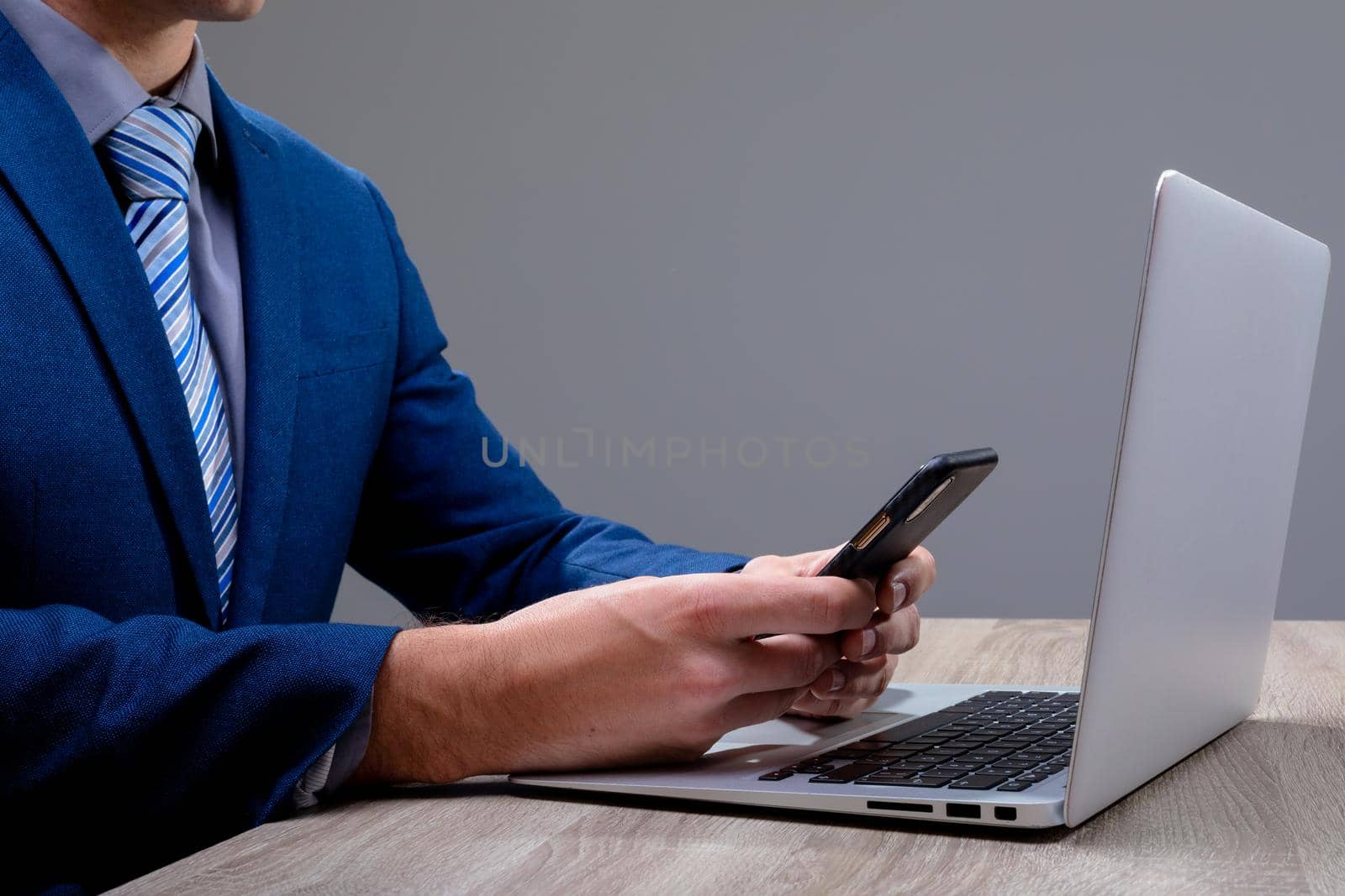 Midsection of caucasian businessman using smartphone and laptop, isolated on grey background. business technology, communication and growth concept digitally generated composite image.