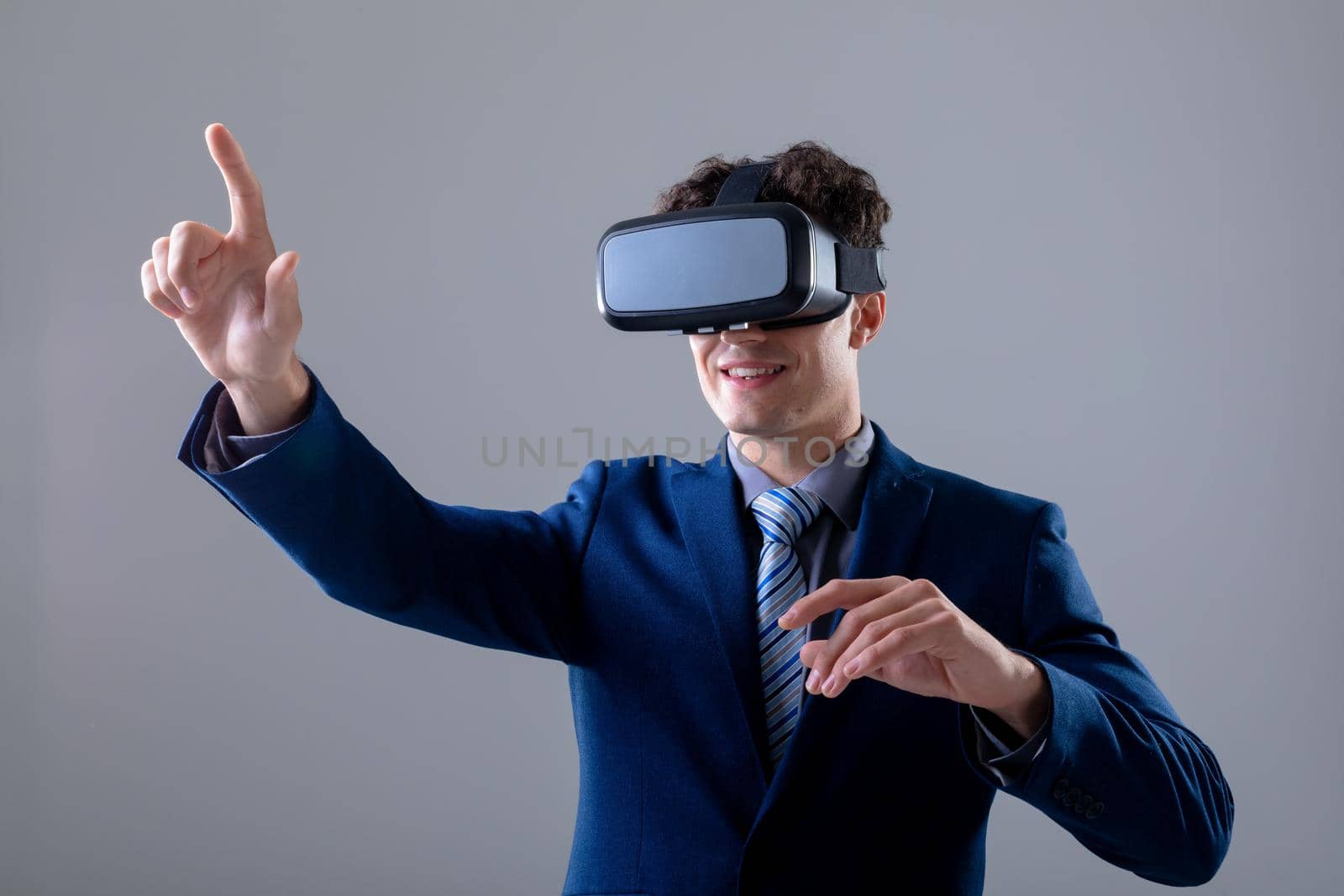 Caucasian businessman wearing vr headset touching virtual interface, isolated on grey background by Wavebreakmedia