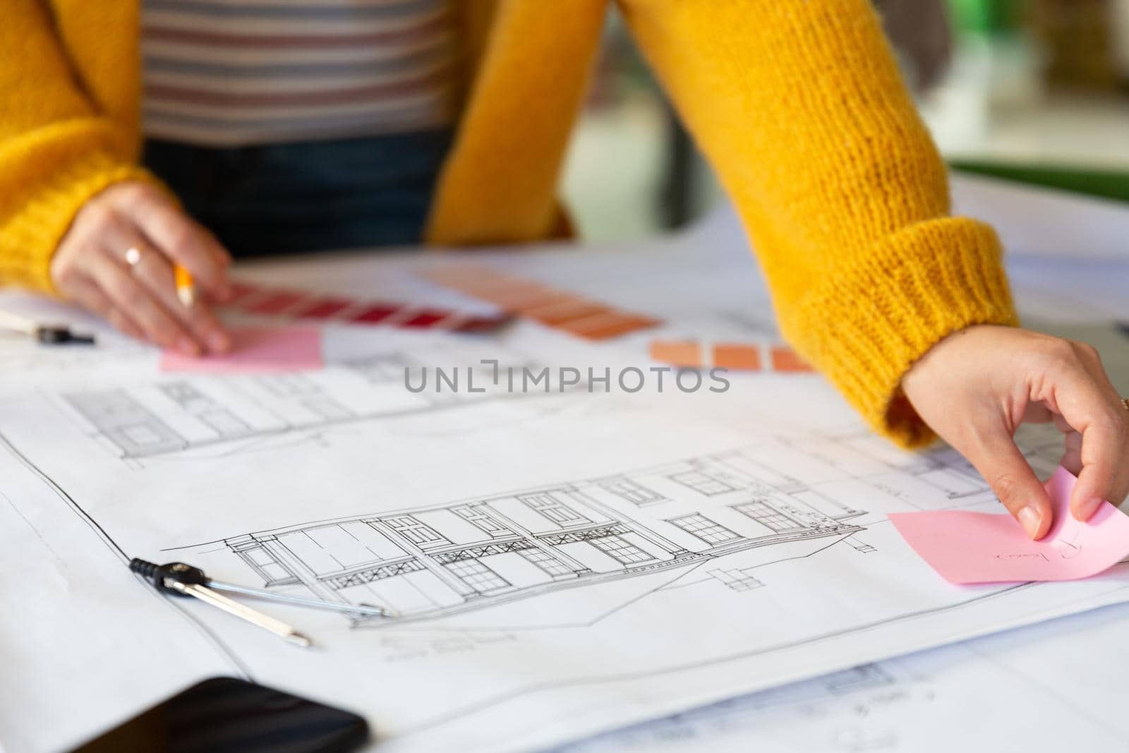 Midsection of caucasian businesswoman writing and placing memo notes on blueprint by Wavebreakmedia
