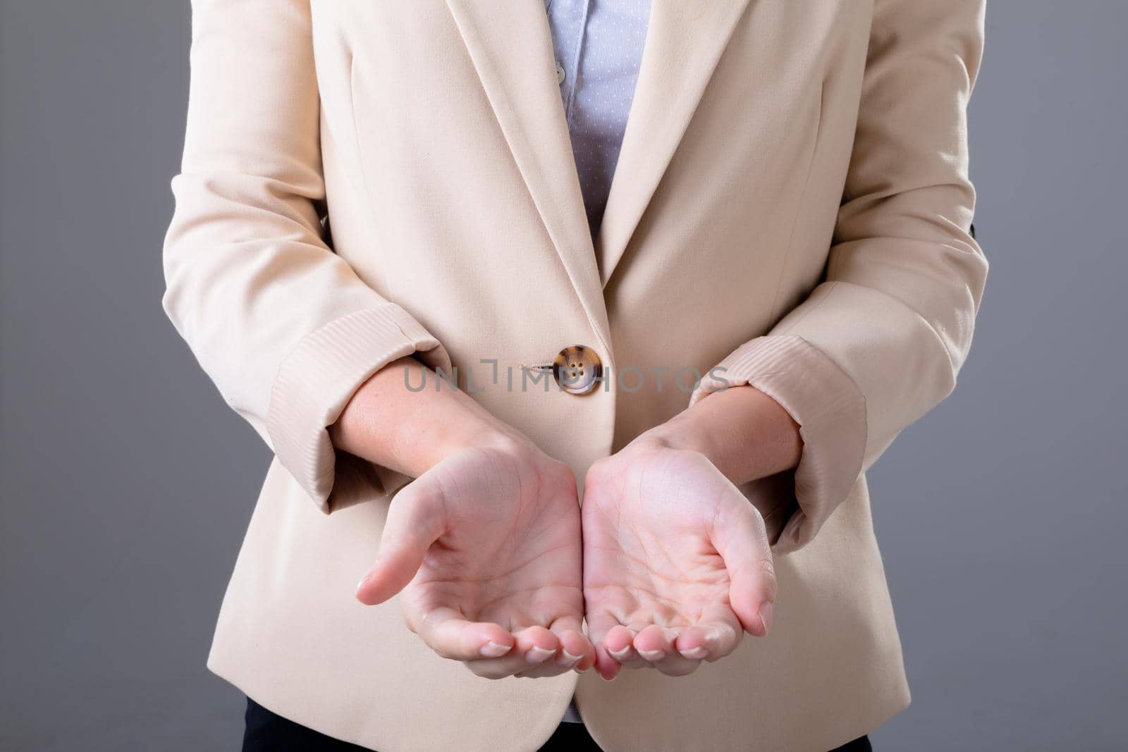 Midsection of caucasian businesswoman showing her hands, isolated on grey background by Wavebreakmedia