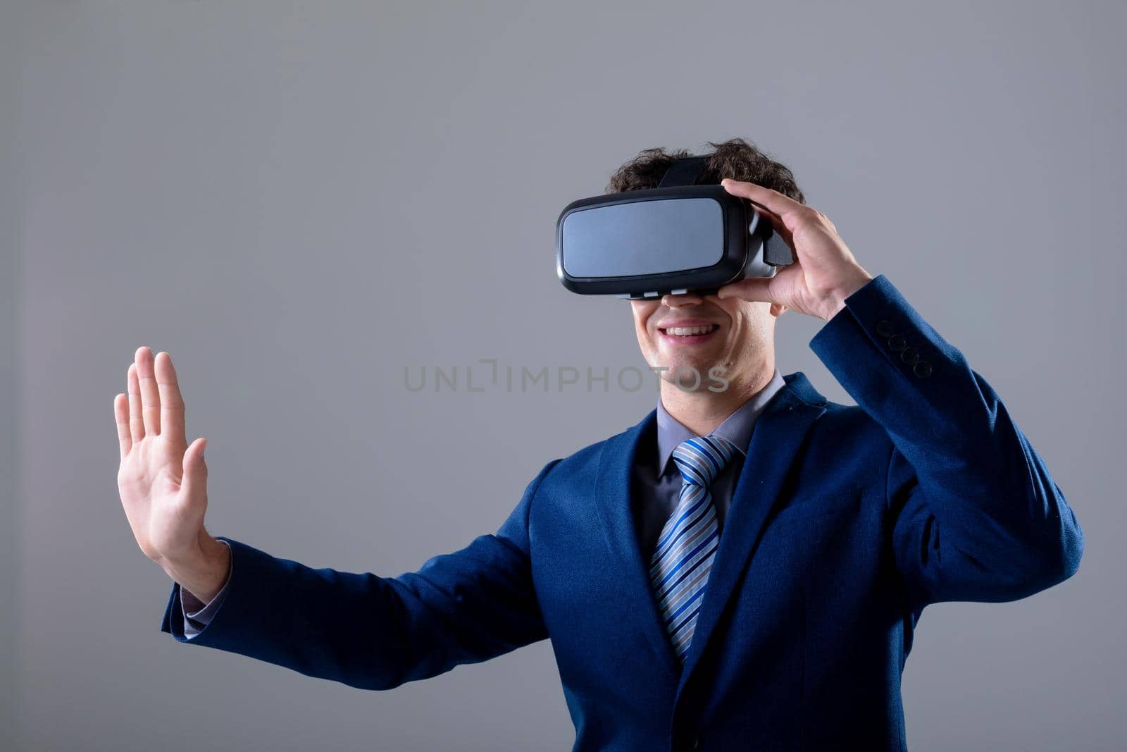 Caucasian businessman wearing vr headset touching virtual interface, isolated on grey background. business technology, communication and growth concept digitally generated composite image.