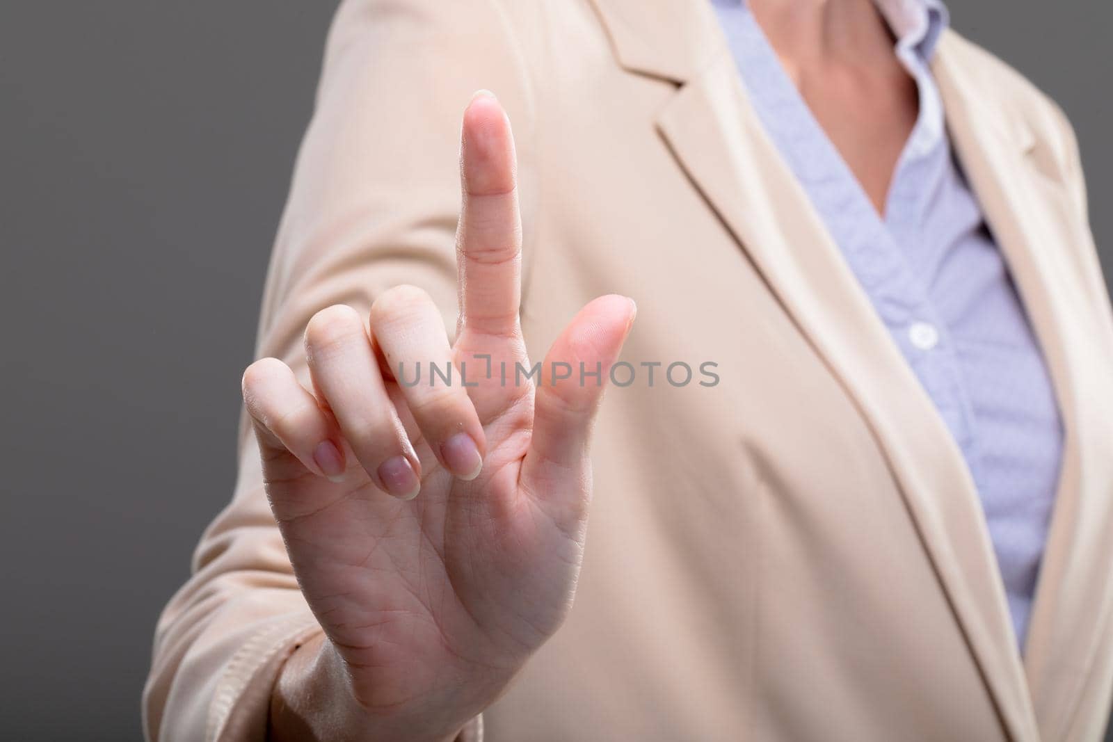 Midsection of caucasian businesswoman touching virtual interface on grey background. business, technology, communication and growth concept.