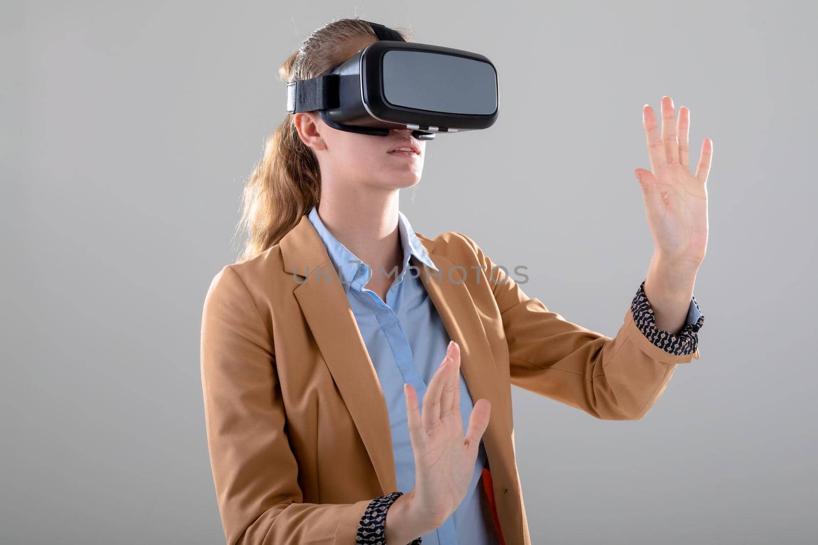 Caucasian businesswoman wearing vr headset touching virtual interface, isolated on grey background by Wavebreakmedia