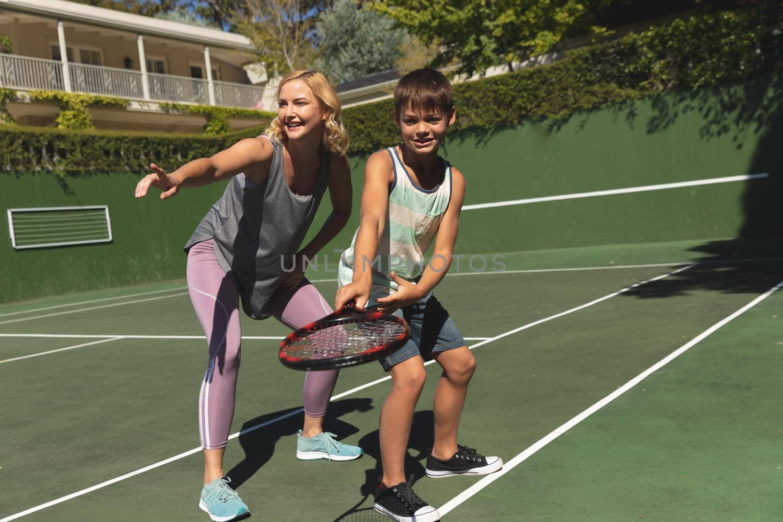Caucasian mother and son outdoors, playing tennis on tennis court by Wavebreakmedia