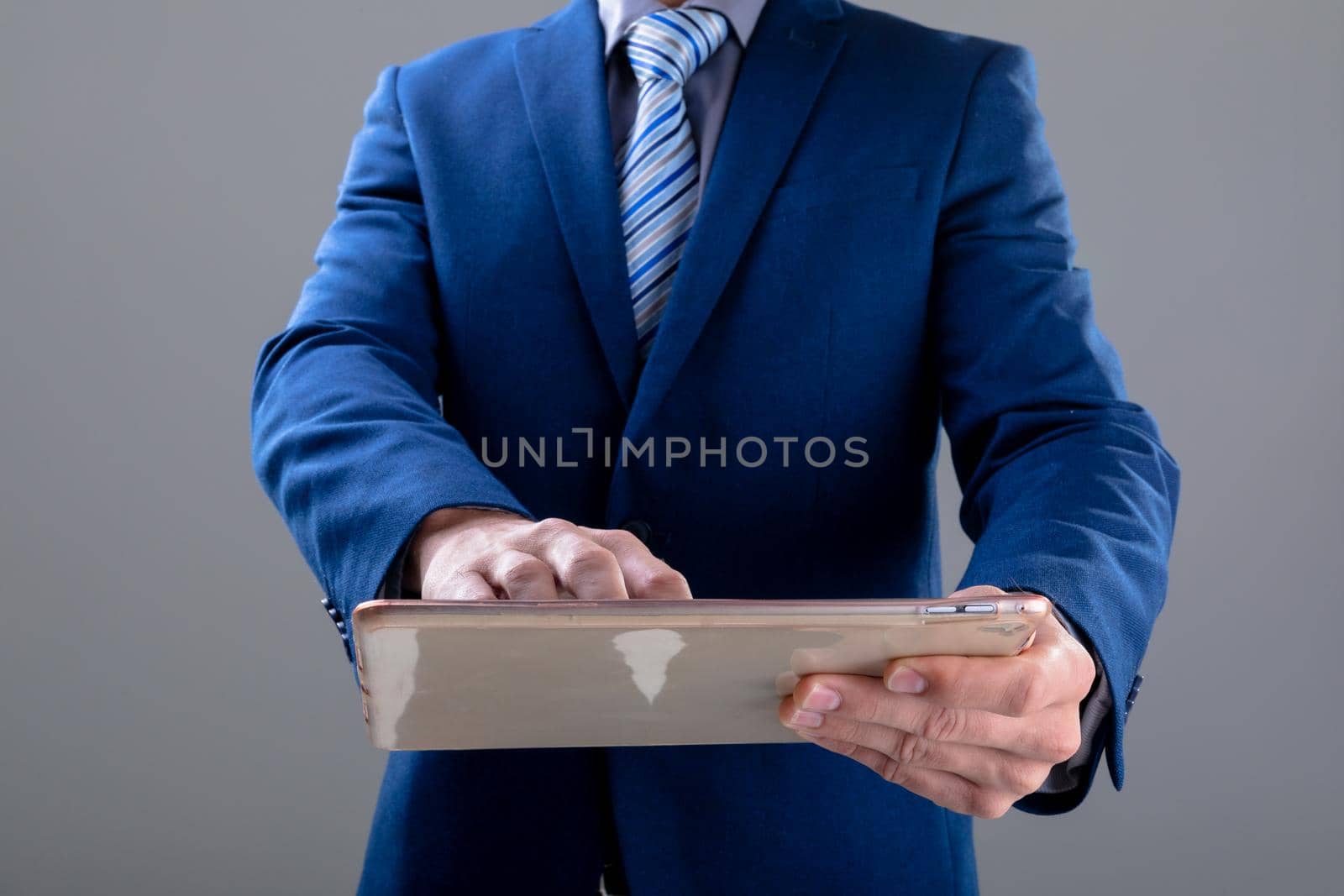 Midsection of caucasian businessman using tablet, isolated on grey background by Wavebreakmedia