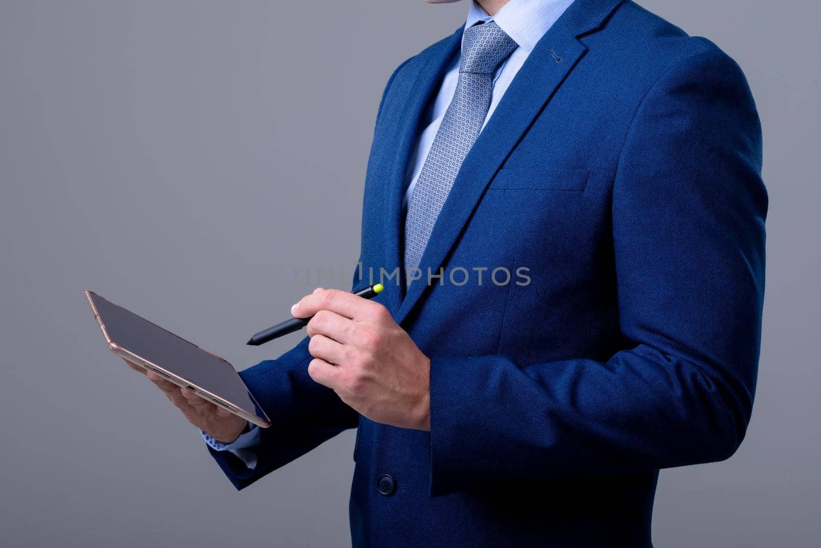 Midsection of caucasian businessman using digital tablet, isolated on grey background by Wavebreakmedia