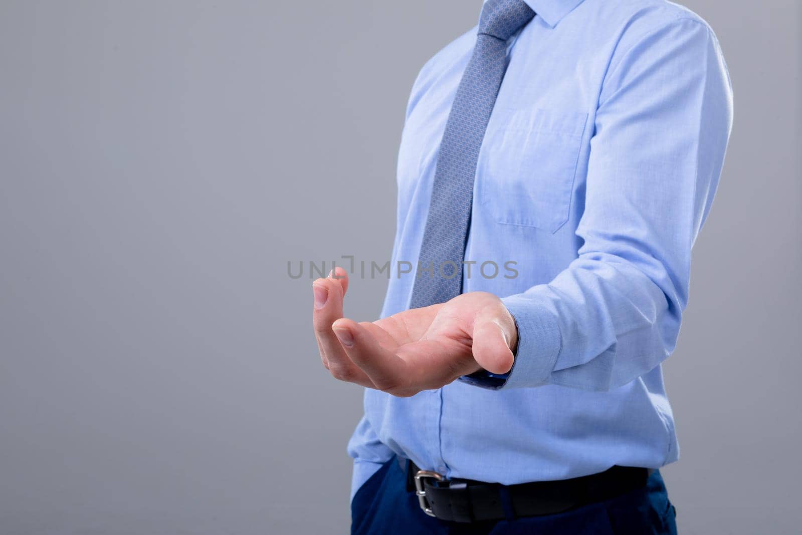 Midsection of caucasian businessman reaching his hand, isolated on grey background. business technology, communication and growth concept.