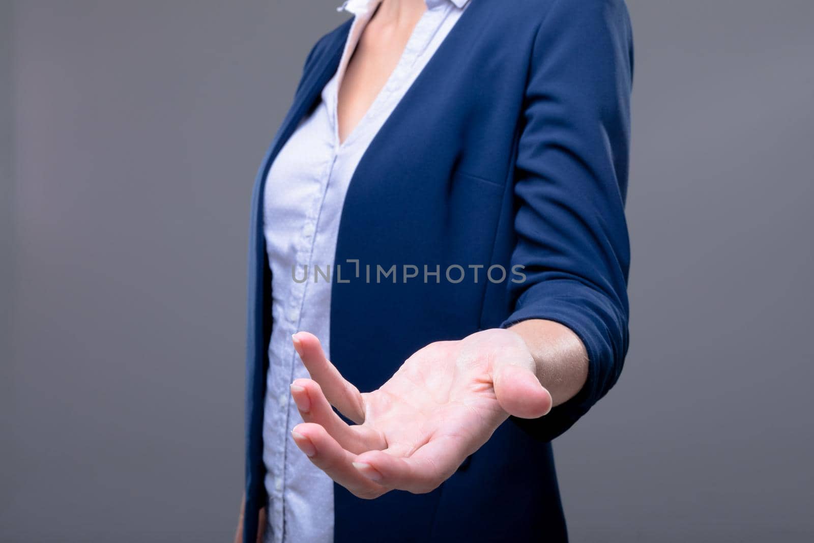 Midsection of caucasian businesswoman reaching with her hand, isolated on grey background. business technology, communication and growth concept digitally generated composite image.