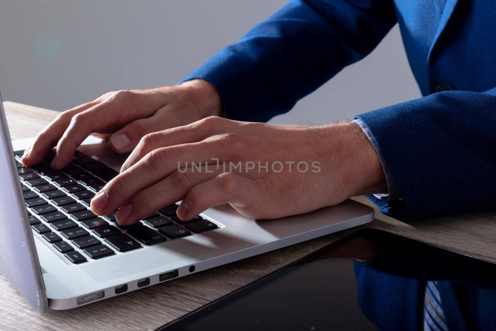 Midsection of caucasian businessman typing on keyboard, isolated on grey background. business technology, communication and growth concept digitally generated composite image.