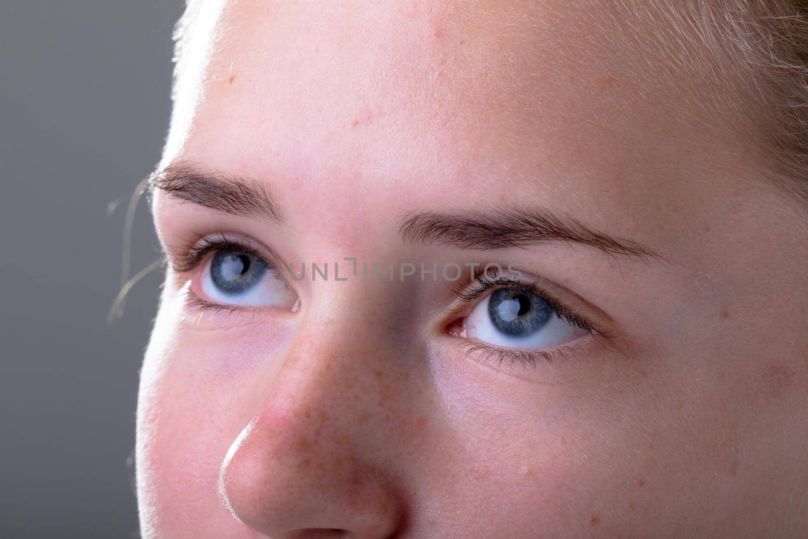 Close up of blue eyes of caucasian businesswoman, isolated on grey background by Wavebreakmedia