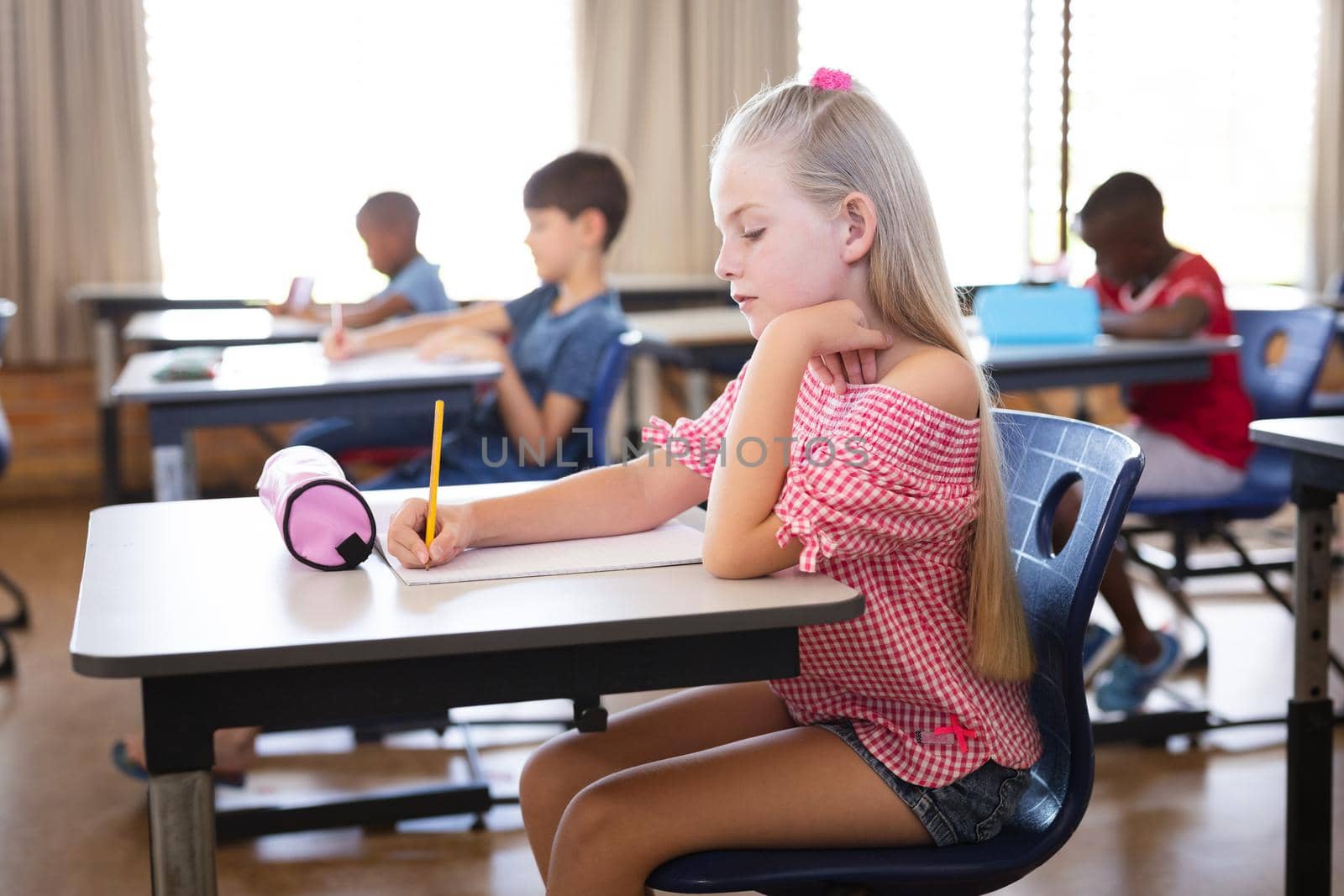 Caucasian girl studying while sitting on her desk in the class at school. school and education concept