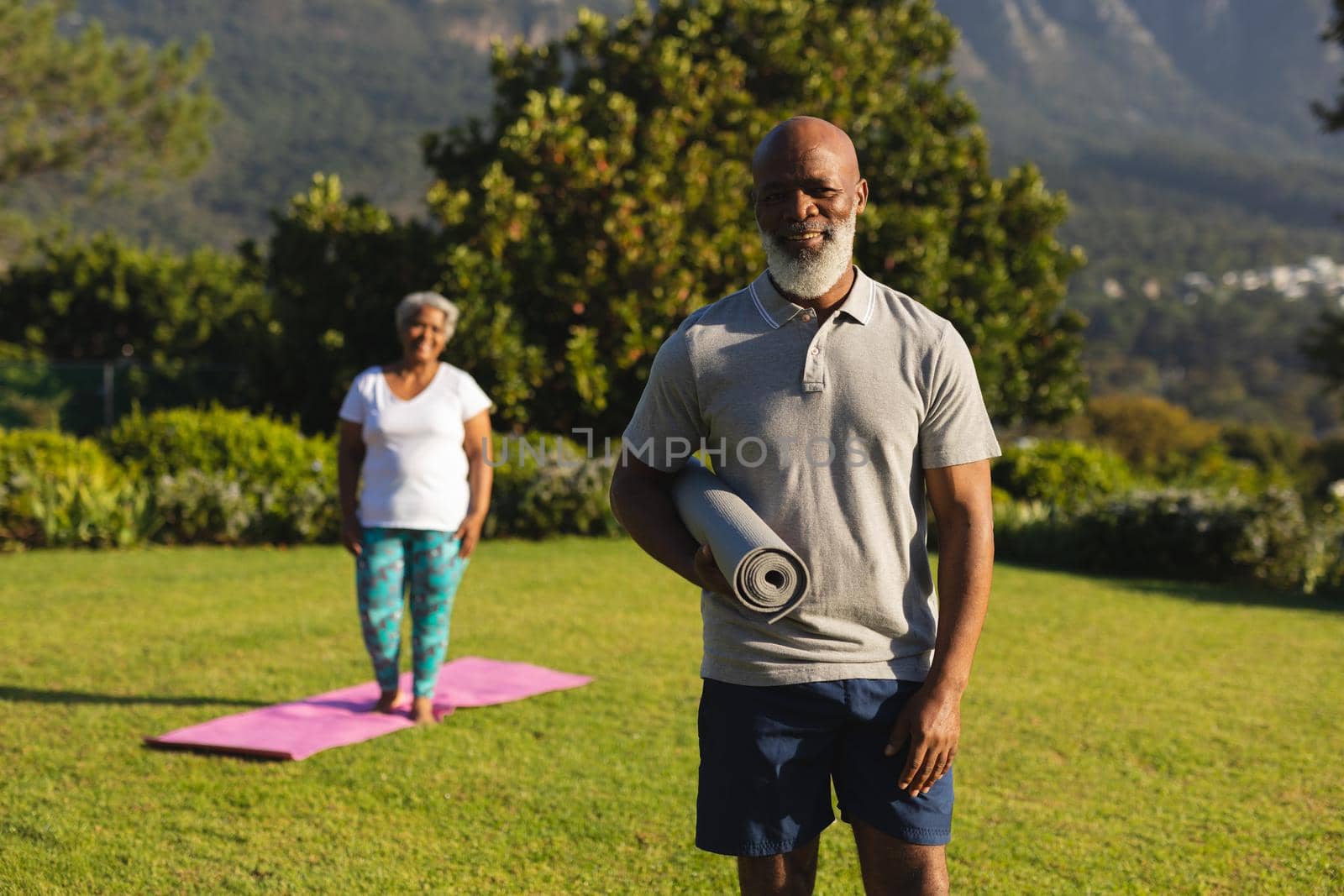 Portrait of smiling senior african american couple with yoga mat in countryside retreat by Wavebreakmedia