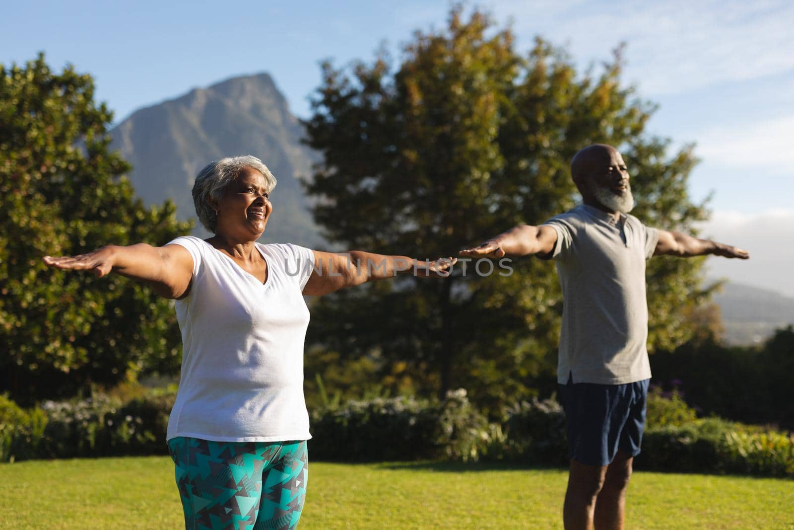 Senior african american couple practicing yoga in stunning countryside retreat. retirement and active senior lifestyle concept.