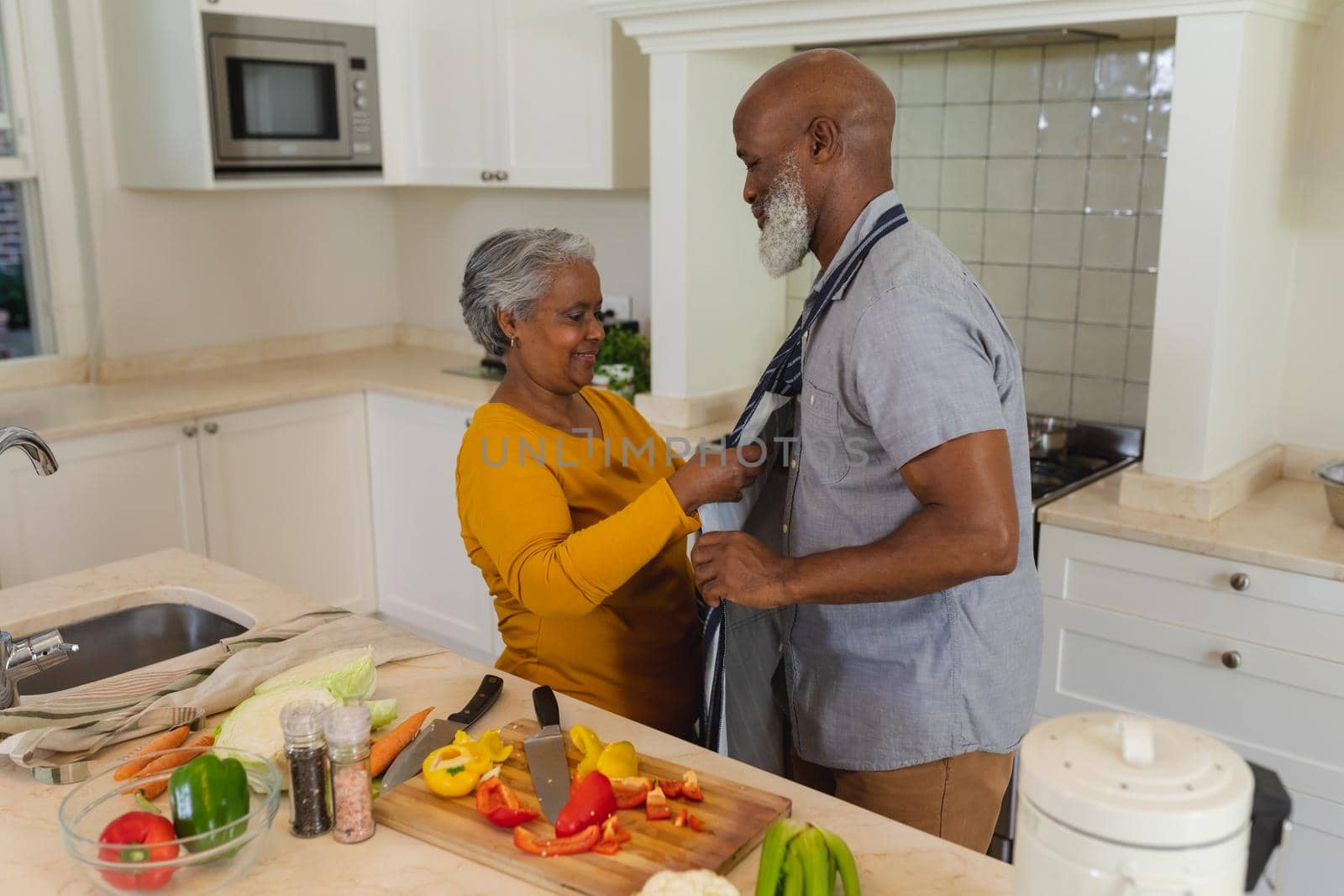 Senior african american couple cooking together in kitchen smiling. retreat, retirement and happy senior lifestyle concept.