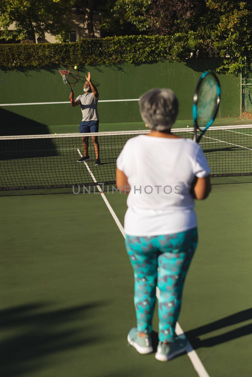 Senior african american couple playing tennis on tennis court. retirement and active senior lifestyle concept.