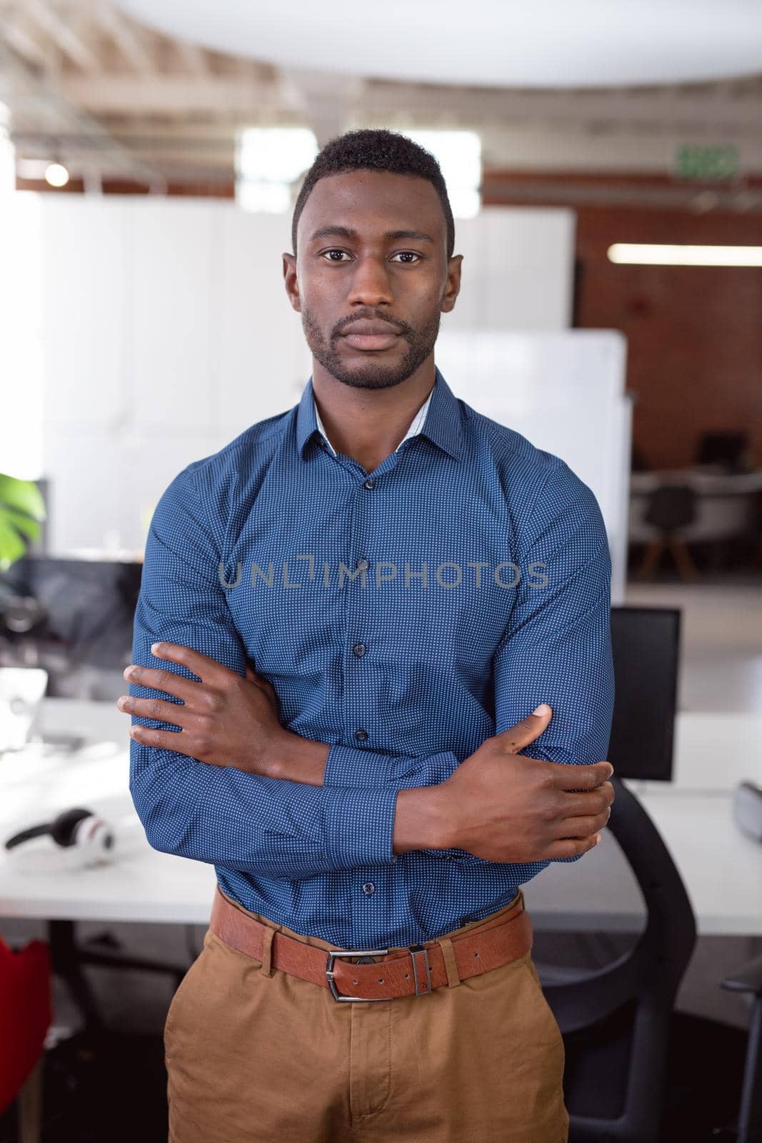 Portrait of african american businessman standing in office with arms crossed looking to camera. working in business at a modern office.