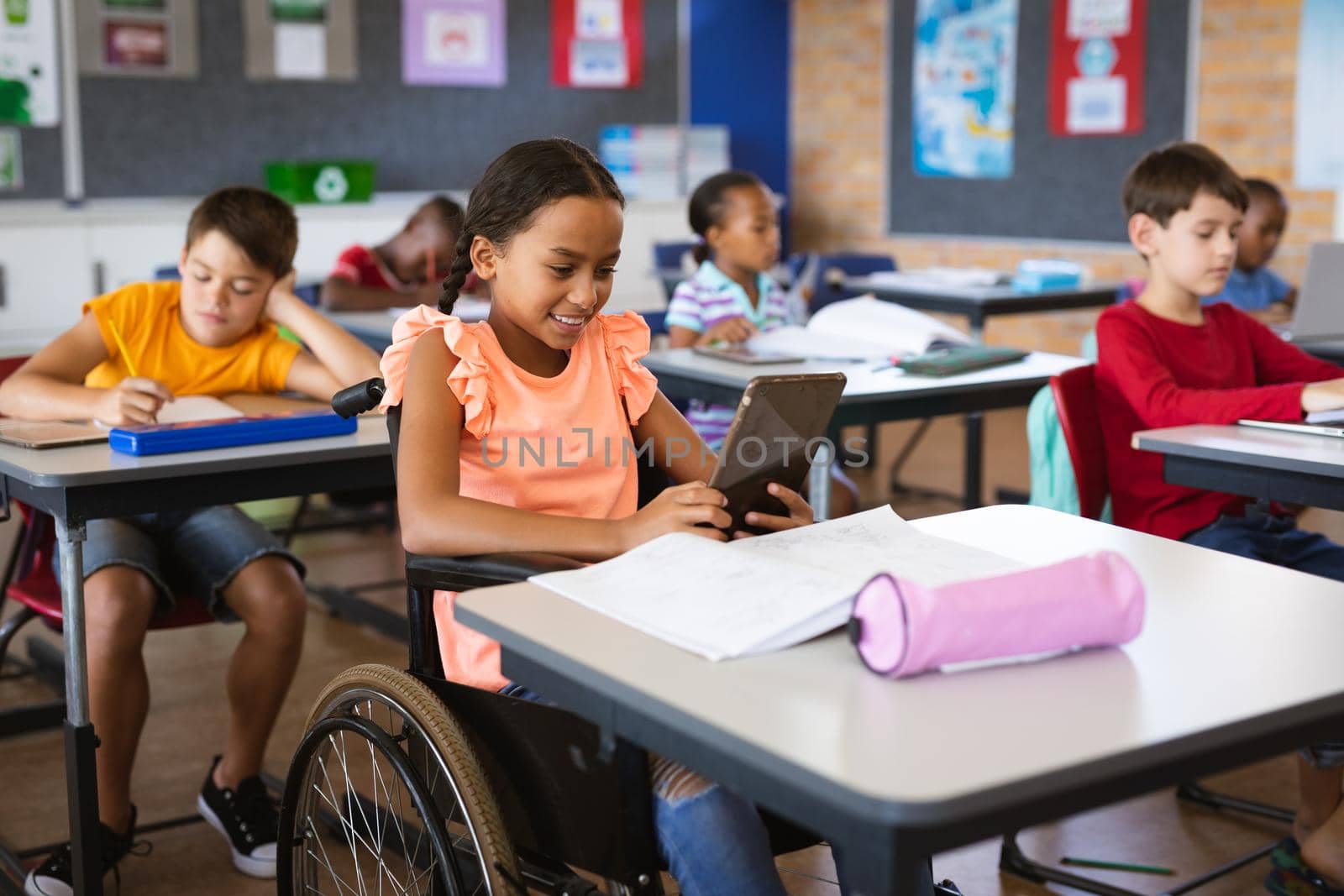 Disabled african american girl using digital tablet while sitting on wheelchair at elementary school by Wavebreakmedia