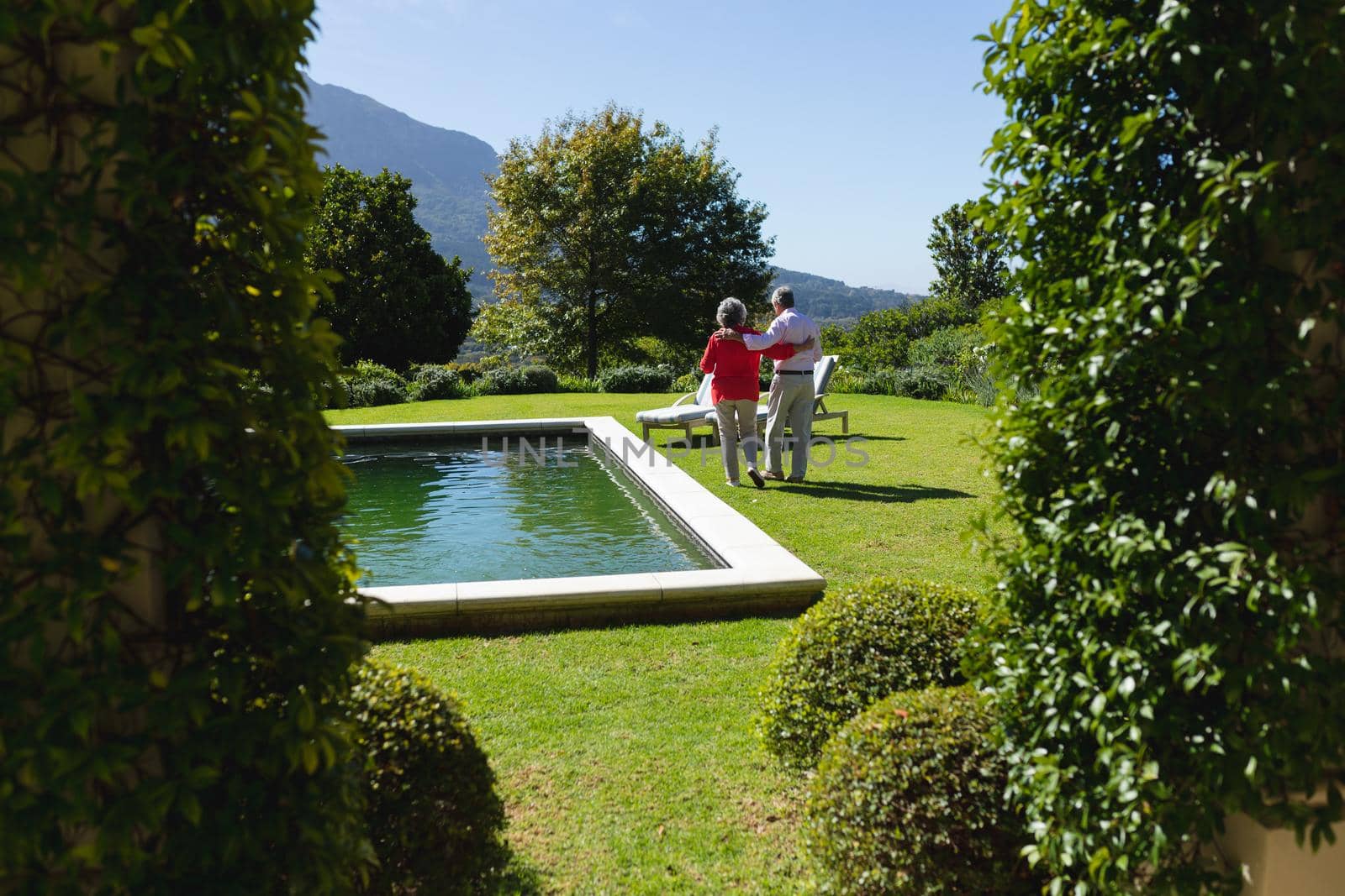 Senior caucasian couple embracing and walking in sunny garden by Wavebreakmedia