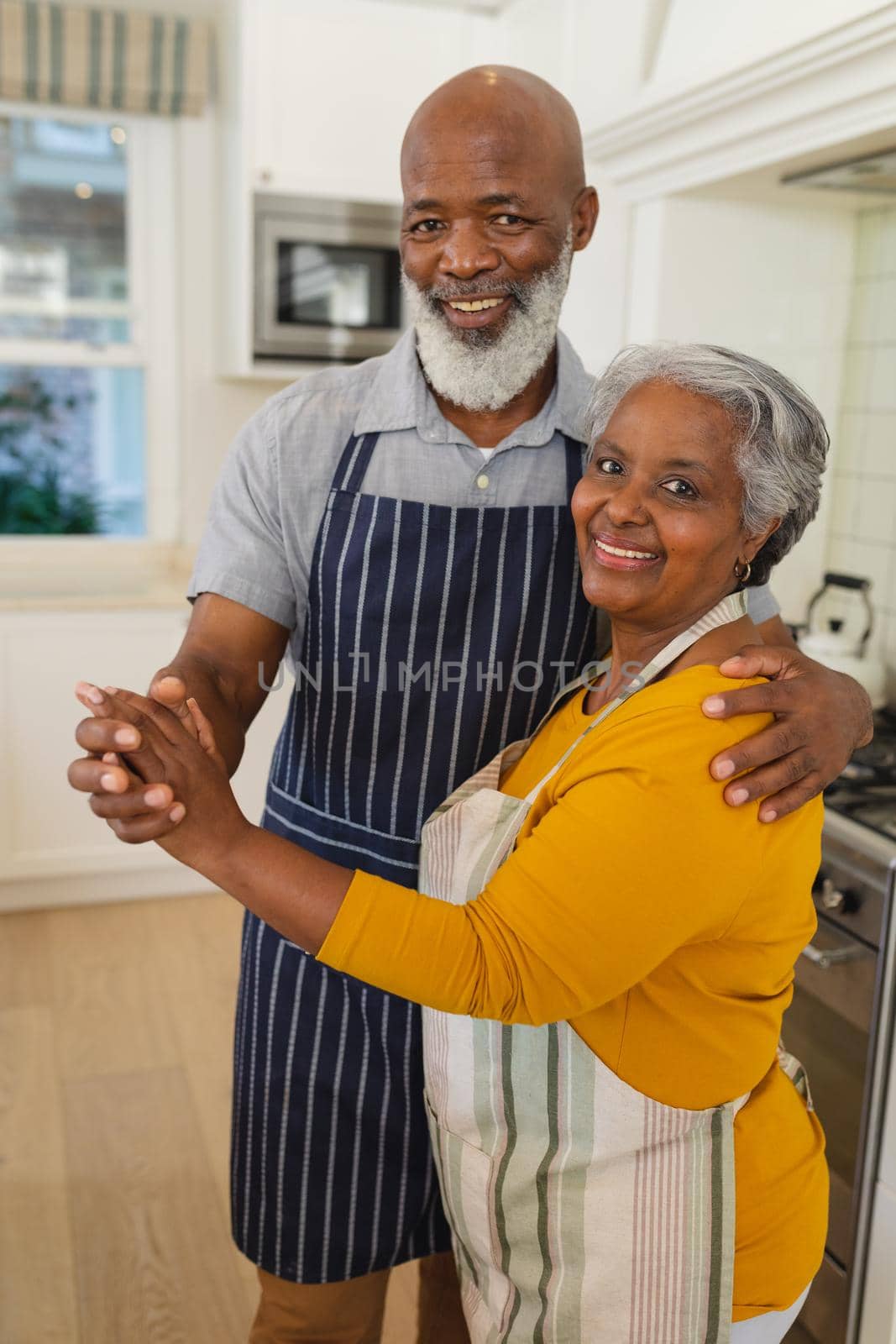 Portrait of senior african american couple in kitchen looking at camera and smiling. retreat, retirement and happy senior lifestyle concept.