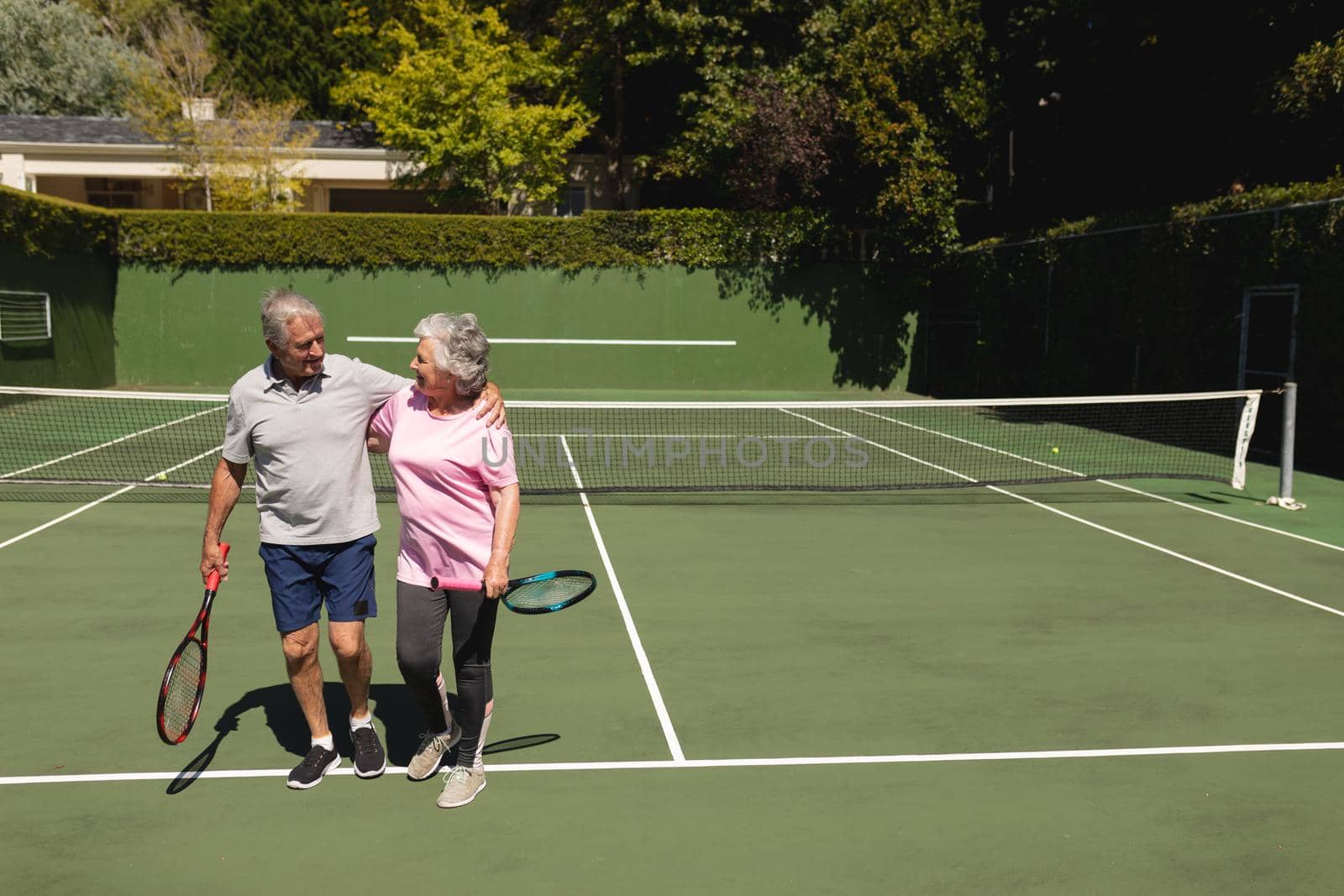 Senior caucasian couple embracing and smiling on tennis court by Wavebreakmedia